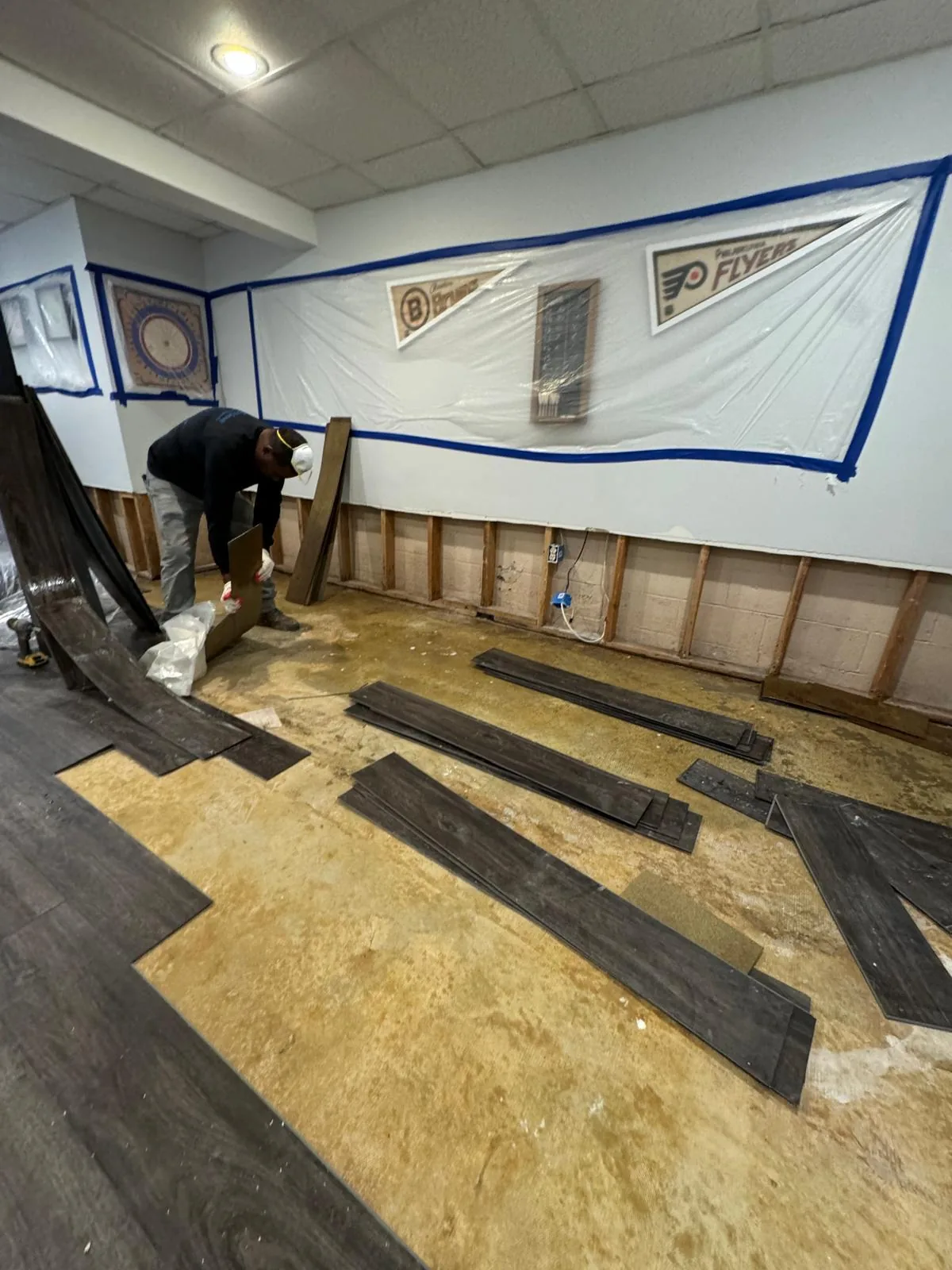 Technician removing water-damaged plank flooring during a basement flood cleanup